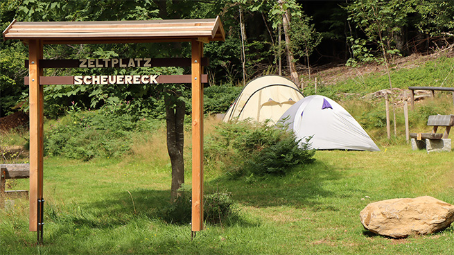 Zeltplatz Scheuereck mit Zelten und einem Hinweisschild