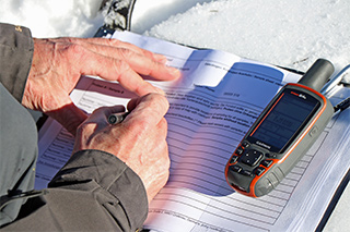 Mitarbeiter notiert Daten von einem GPS-Gerät