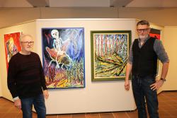 Der Borkenkäfer und der neu nachwachsende, wilde Wald: Josef Schneck (l.) und Christian Binder, Leiter vom Waldgeschichtlichen Museum, zeigen zwei Malereien, die in der Ausstellung zu sehen sind. (Foto: Nationalpark Bayerischer Wald)