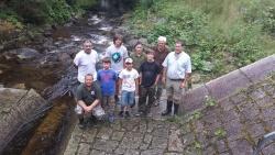 Josef Hoch von der Fischereifachberatung des Bezirks Niederbayern (hinten rechts) und Burkhard Beudert vom Nationalpark Bayerischer Wald (vorne rechts) mit 1. Gewässerwart Christian Bummer (hinten links) und 1. Jugendleiter Jürgen Knörzer (vorne links) mit Jugendlichen vom ASV Landshut an der umgebauten Pegelanlage Taferlruck mit der „Rauen Rampe“ im Hintergrund.