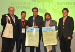 Grenzenlose Freude über die erneute Auszeichnung: die beiden Nationalpark-Leiter Dr. Franz Leibl (Bayerischer Wald; Mitte) und Pavel Hubený (Šumava; 2. von rechts) sowie die verantwortlichen Sachgebietsleiter Hans Kiener (Bayerischer Wald; links) und Martin Starý (Šumava; rechts) mit dem druckfrischen „Transboundary“-Zertifikat aus den Händen von EUROPARC-Präsident Ignace Schops (2. von links). Bi