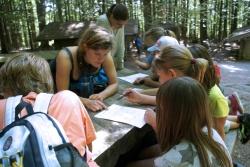 „Neue Impulse zum Wohle der Natur“: die Commerzbank-Umweltpraktikantin Stefanie Jessolat (Mitte) mit Kindern bei der Sommer-Rallye 2015 im Waldspielgelände bei Spiegelau im Nationalpark Bayerischer Wald. Bild: Alice Alteneder, NPV BW